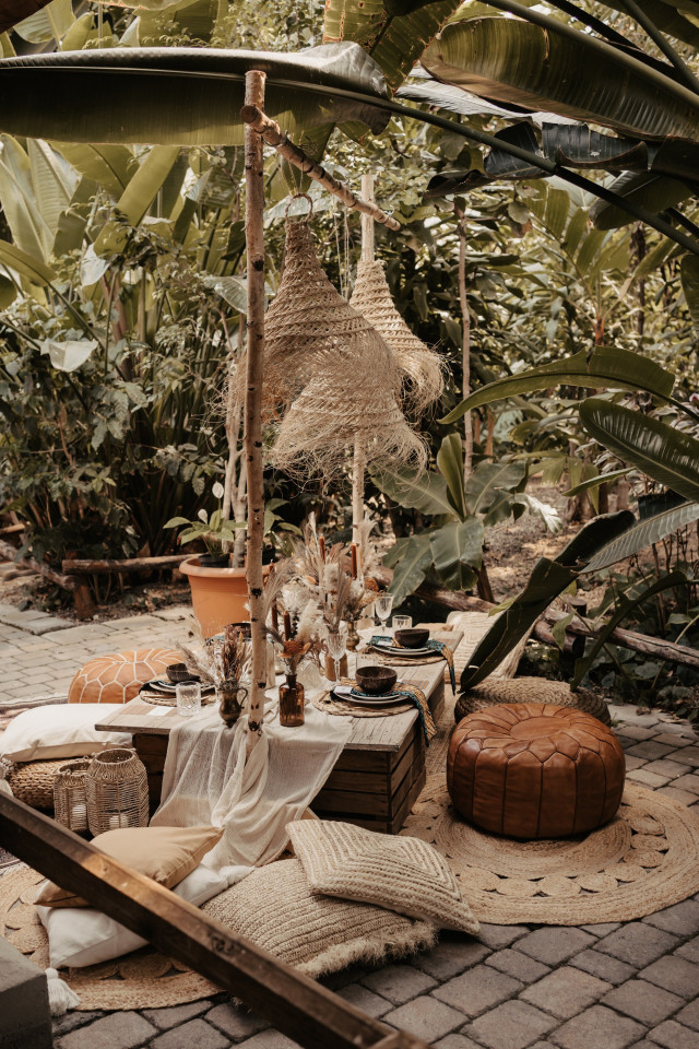 Boho Hochzeitstisch mit Sitzkissen auf dem Boden in einem botanischen Garten