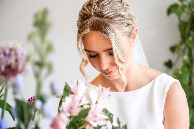 Mariée regardant doucement vers le bas, entourée de fleurs pastel