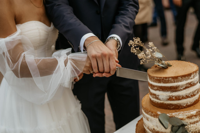 Hochzeitstorte wird von Brautpaar angeschnitten
