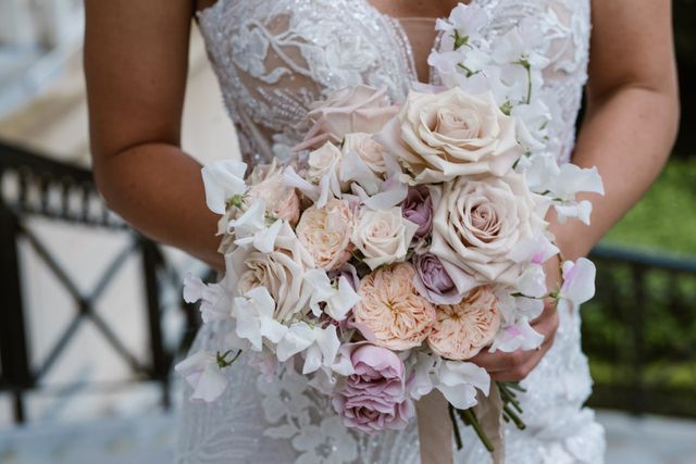 Close-up of a romantic bridal bouquet of pink and cream roses with white flowers.