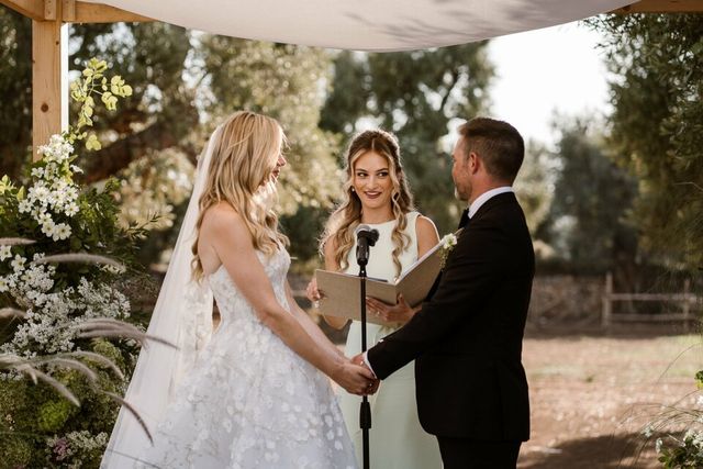 A bride and groom hold each other's hands during the middle of their ceremony.