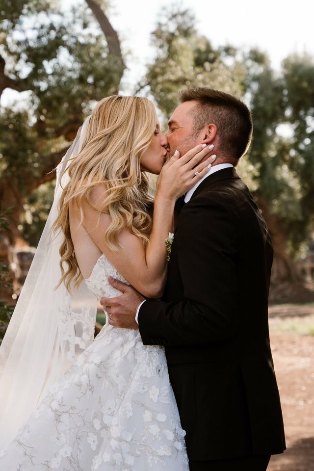 The couple shares an intimate kiss in a Mediterranean garden.
