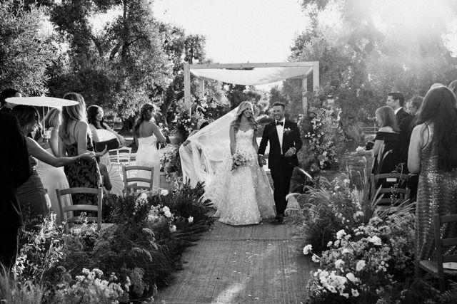 The couple walks back up the aisle between cheering guests after the ceremony.