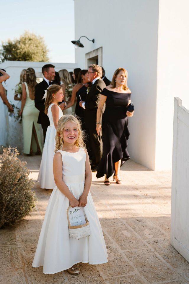 A laughing flower girl in a white dress holds a basket at the front.