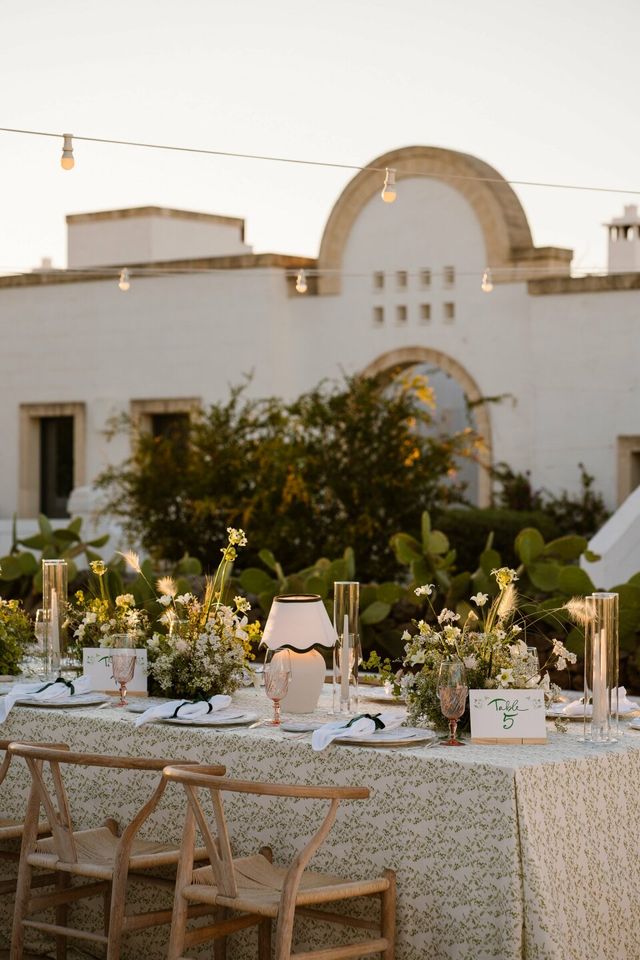 A detail of an ornately set table with flowers, candles, and a printed table number.