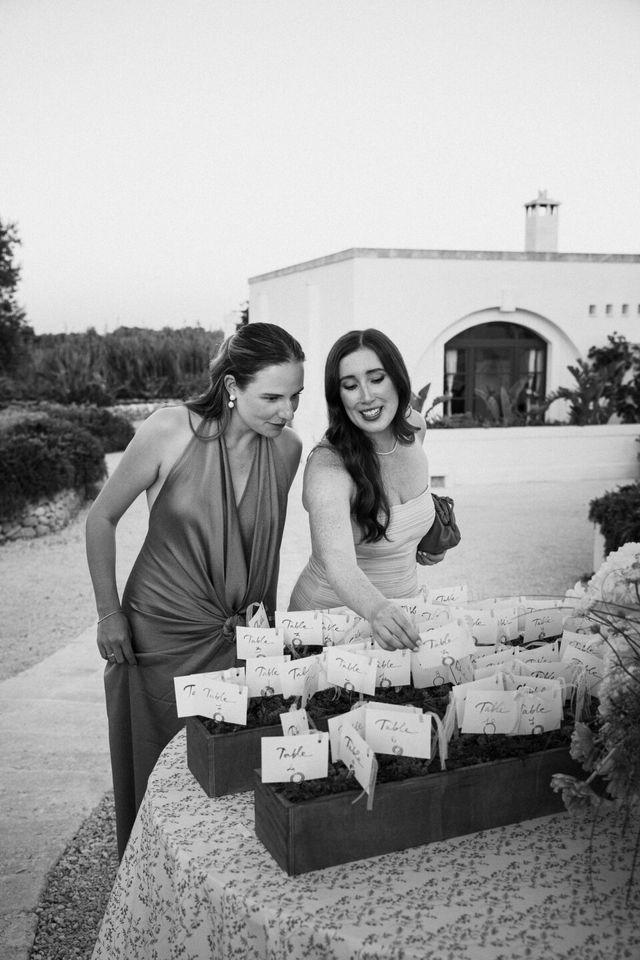 Two guests look for their name cards at the seating display before dinner.