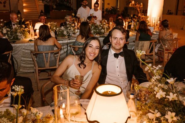 A guest couple poses happily together at the long reception dinner table.