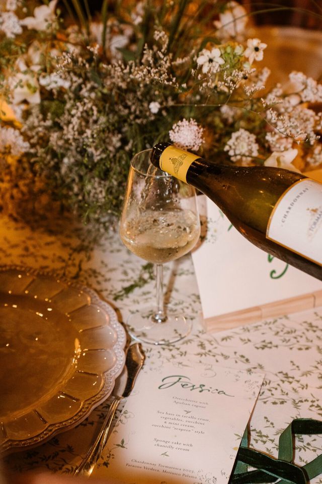 A detail of champagne poured at a table set with gypsophila and printed cards.