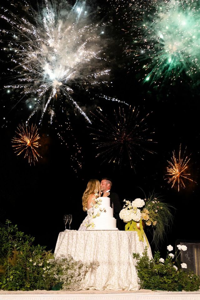 The couple shares a kiss behind their wedding cake during the celebration.