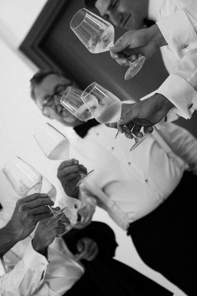 Hands raise wine glasses in a toast over the dinner table.