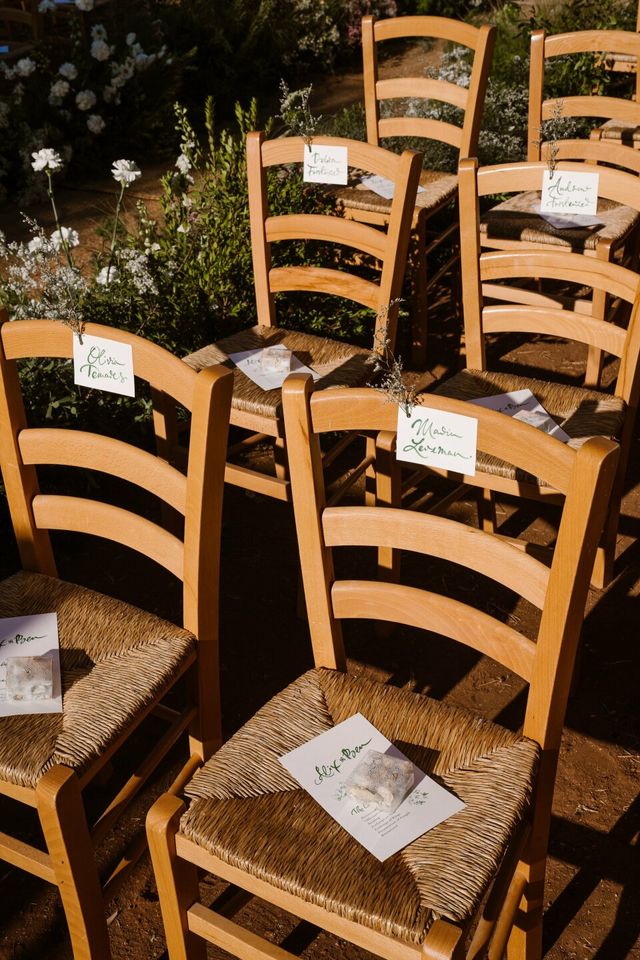 Woven chairs holding handwritten place cards and ceremony programs.
