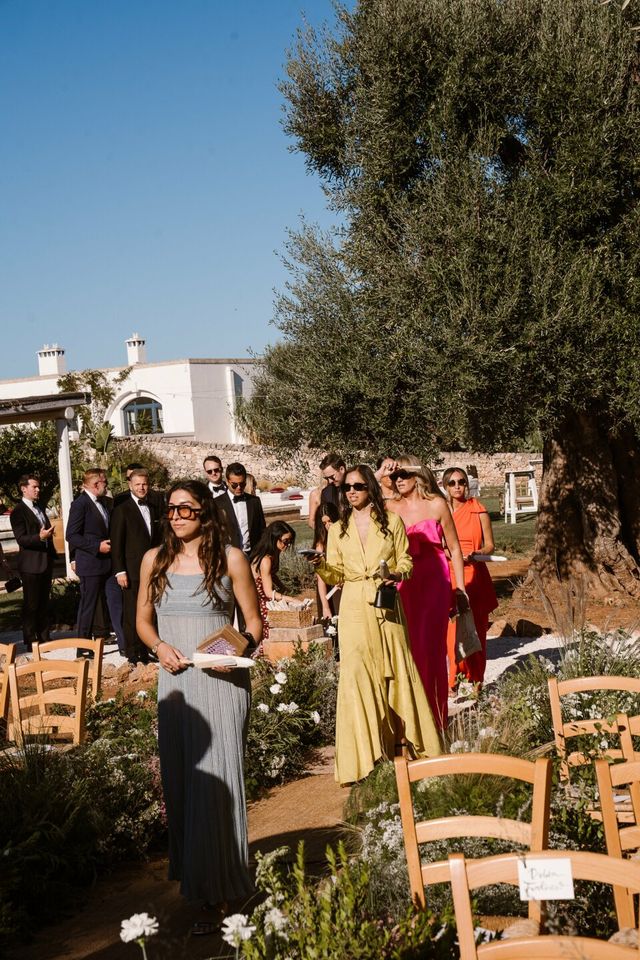 Colorful, well-dressed guests walk and wait near the wedding.