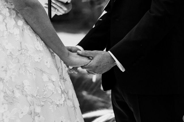A black and white detail of the couple's intertwined hands.