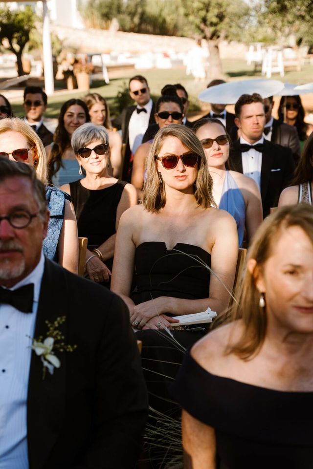 Seated guests in formal attire watch the ceremony in black and white.