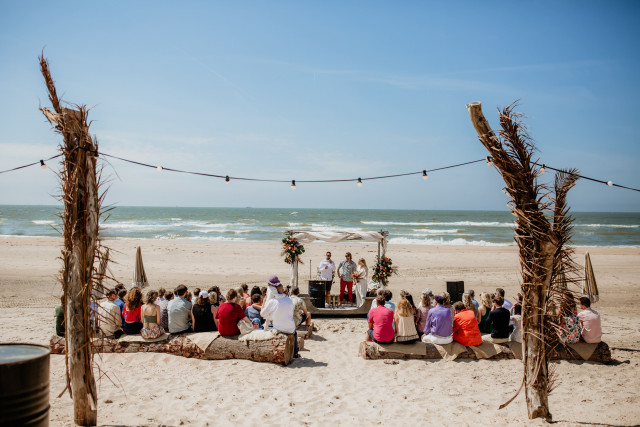 Demoiselle d'honneur sur la plage soulevant la robe de mariée