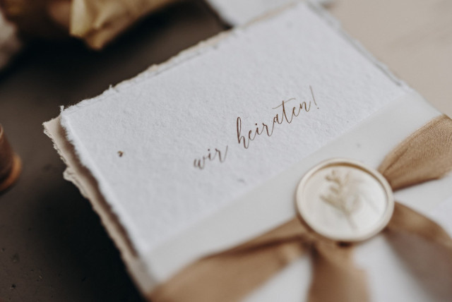 Nahaufnahme einer kleinen Hochzeitskarte mit goldener Aufschrift "Wir heiraten"