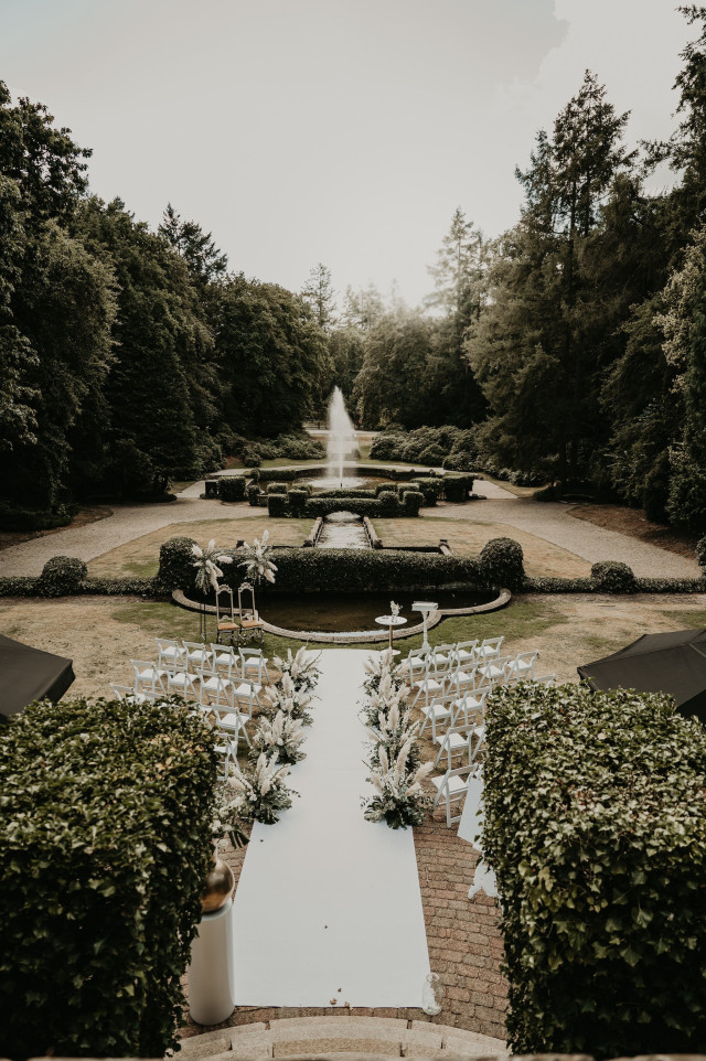 Drohnenaufnahme eines Parks in dem Stühle für eine Trauzeremonie aufgebaut sind