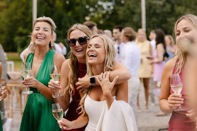 Groep vriendinnen lacht met champagneglazen, buiten