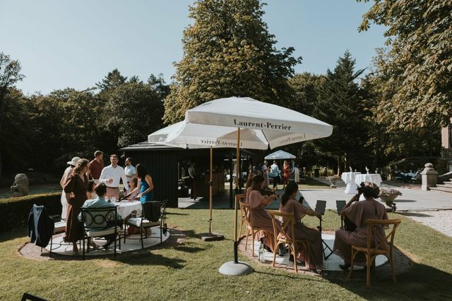 een groep mensen die onder een parasol in een park zitten
