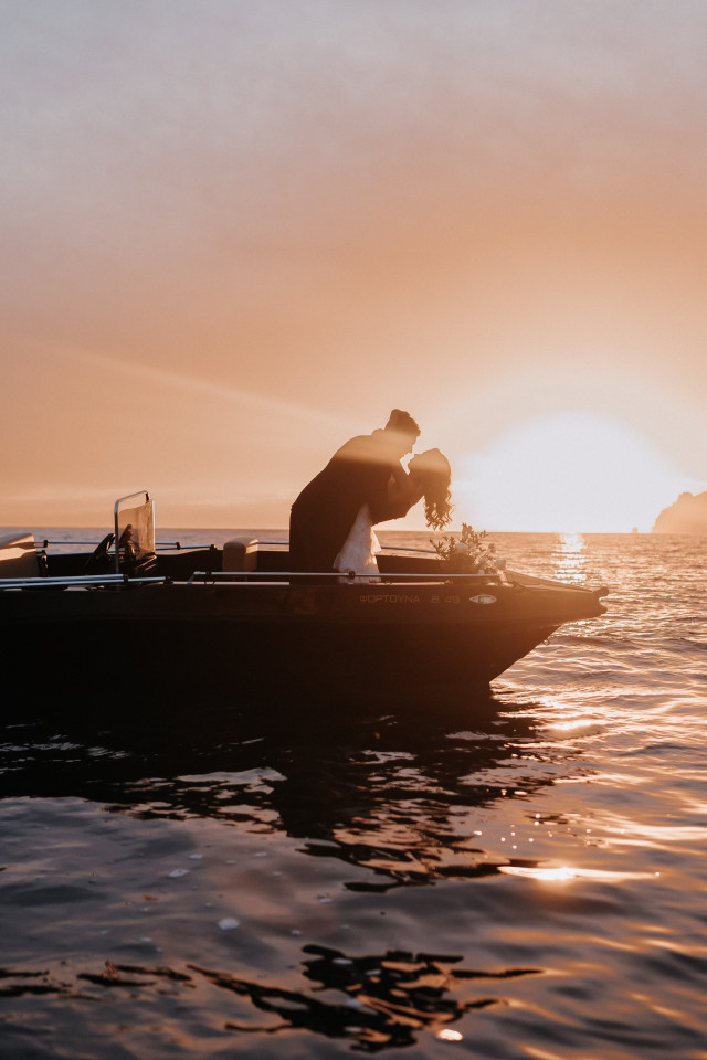 Brautpaar bei Sonnenuntergang auf einem Boot im Meer