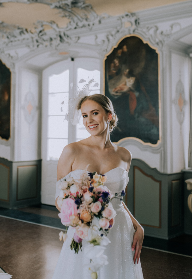 Braut in Schlosssaal mit Brautstrauß