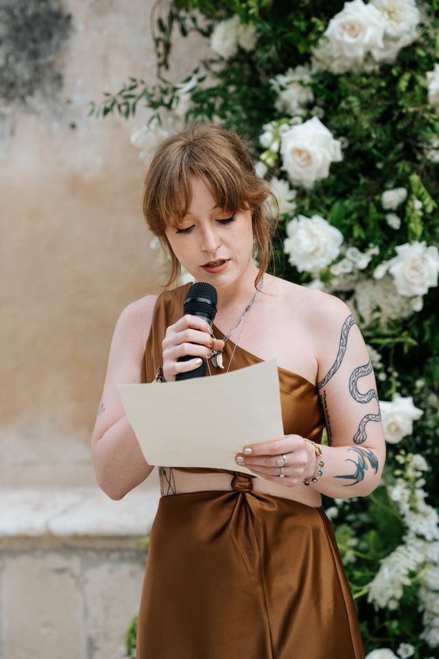 een vrouw met tatoeages houdt een toespraak op een bruiloft