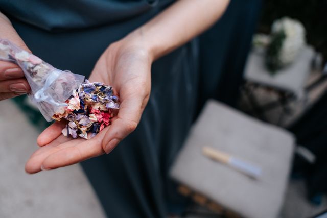 A close-up of hands holding colorful dried flowers in soft light.