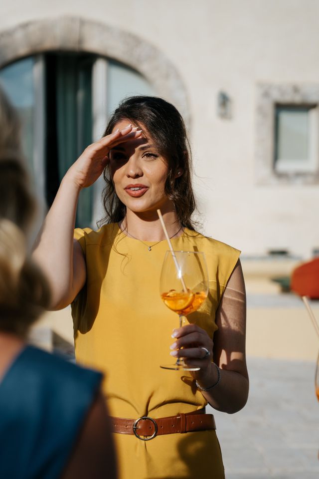 A female guest in a yellow dress holds an Aperol spritz.