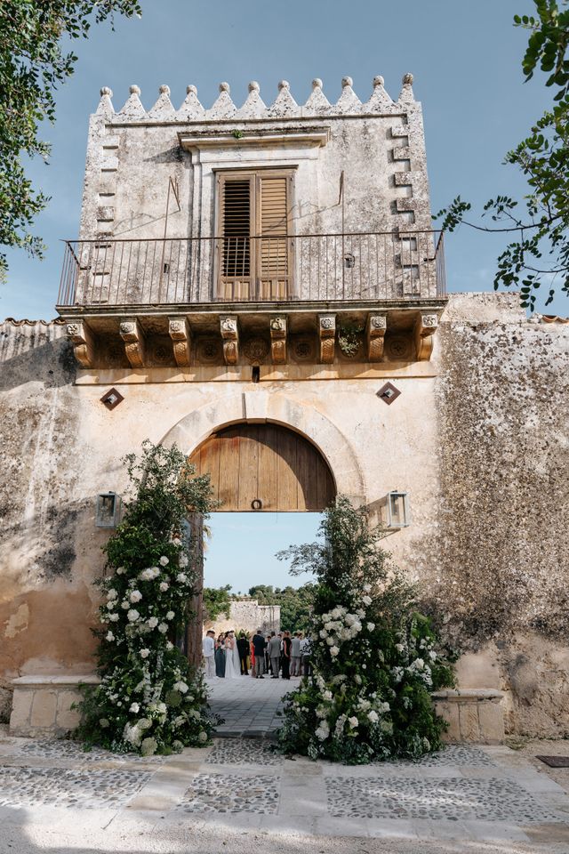 A historic wedding venue with a gate and balcony decorated with flowers.