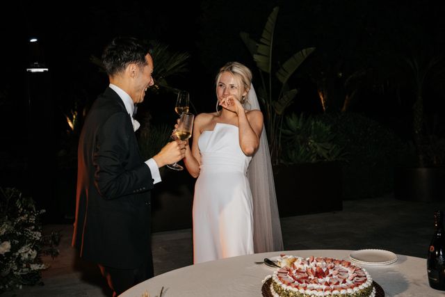 The bride laughs as she tastes a bite of wedding cake during the celebration.