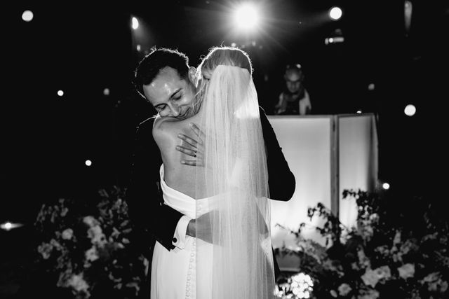 A black and white photo of the couple embracing closely during the day.