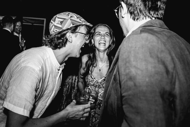 A black and white photo of three laughing guests in animated conversation.