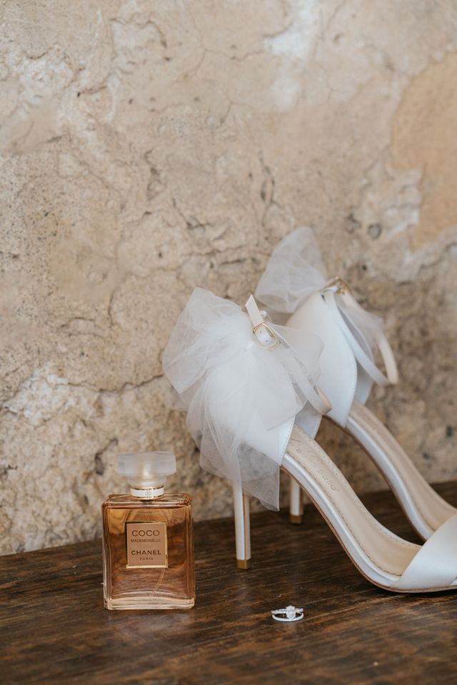 A bottle of perfume styled beside white florals at the getting-ready table.