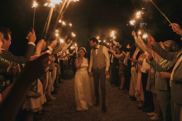 The couple walks hand in hand through an honor guard archway formed by their guests.