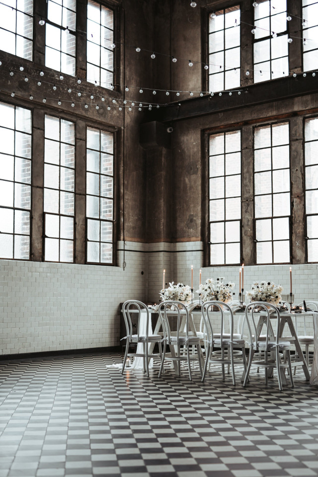 Hochzeitstisch in industrieller Umgebung mit schwarzen und weißen Blumen