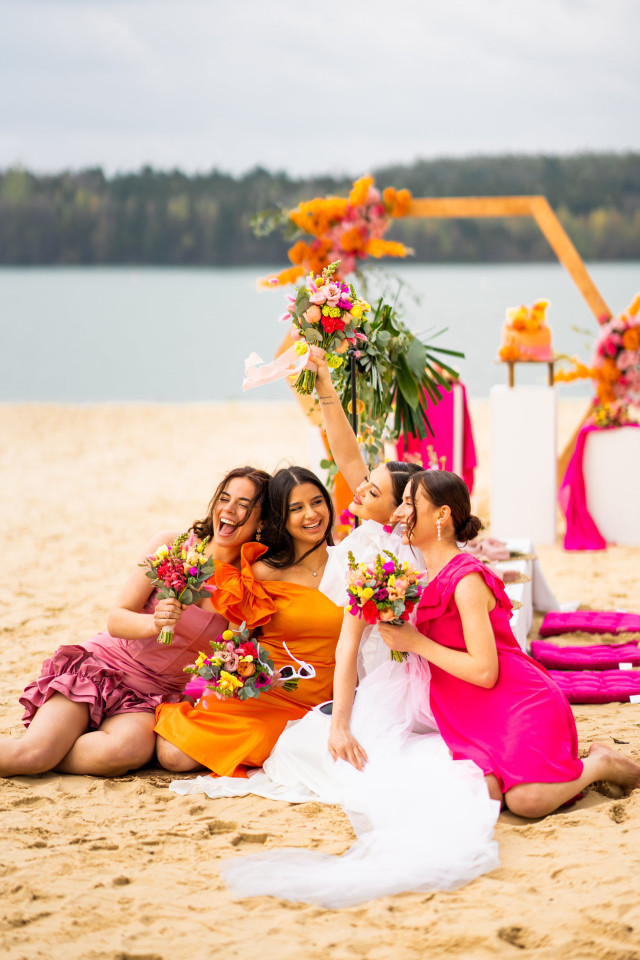 Braut und Brautjungfern sitzen am Strand