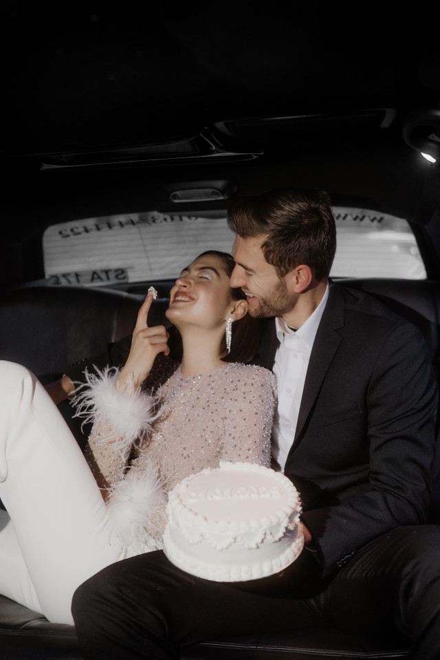 Braut isst glücklich Hochzeitstorte mit dem finger, man sieht Braut verliebt an und hält Hochzeitstorte
