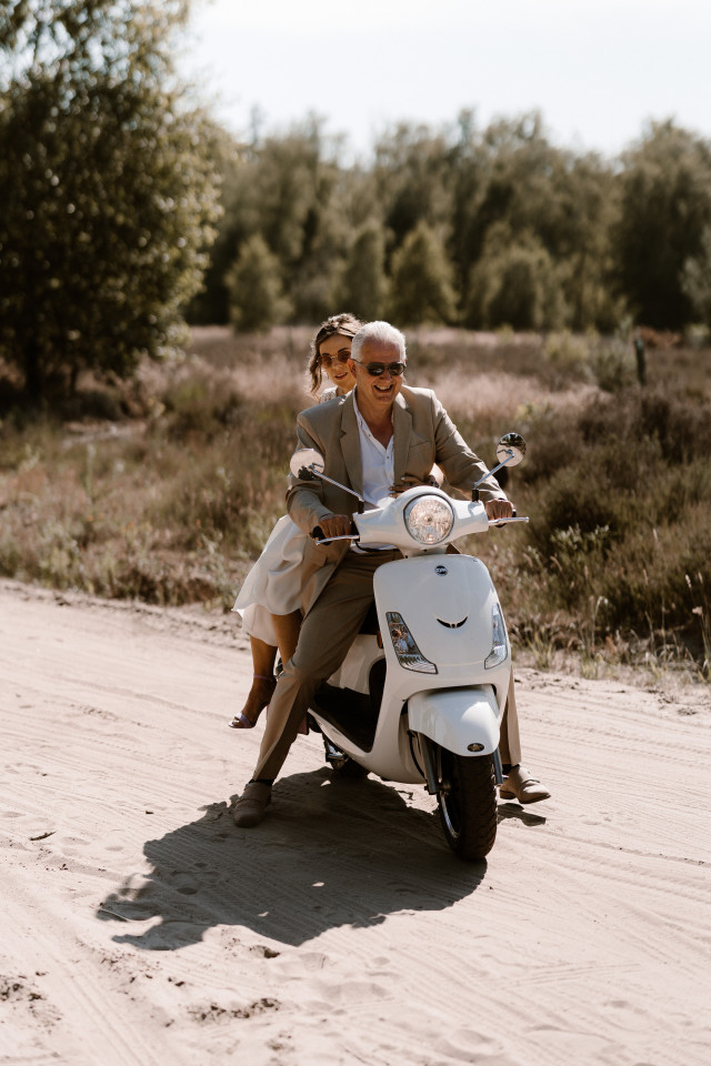 bruid komt aan op locatie met vader op scooter