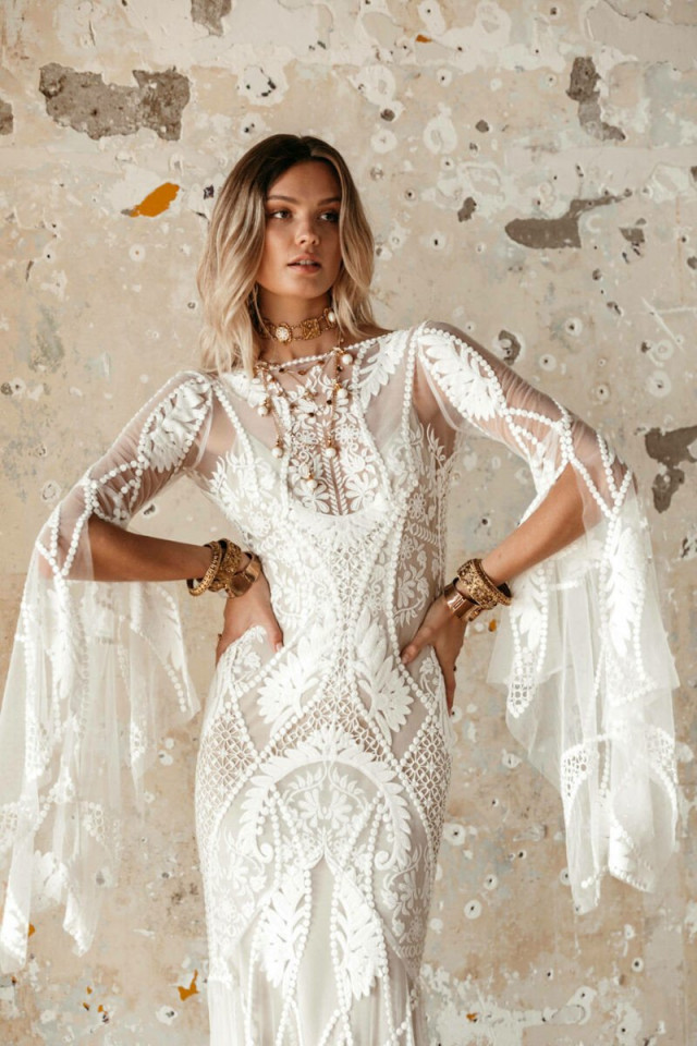 Blonde Braut in Boho Brautkleid mit spitzen verzierhrten Ärmeln