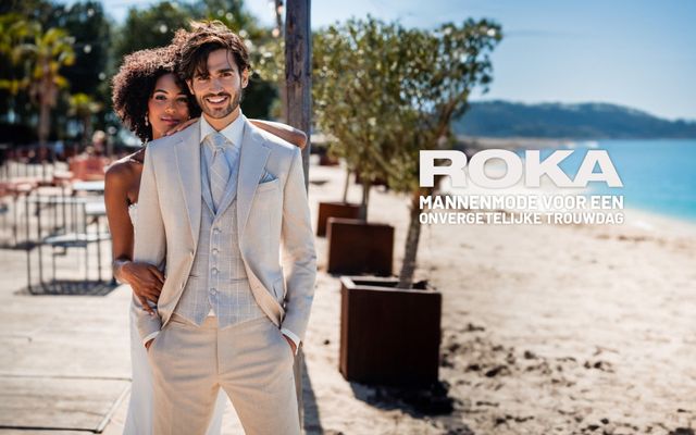 een man en vrouw in witte pakken die op het strand staan