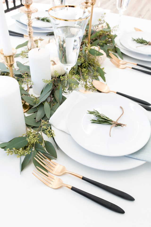 Goldenes Besteck auf elegantem Tisch mit grünen Blättern