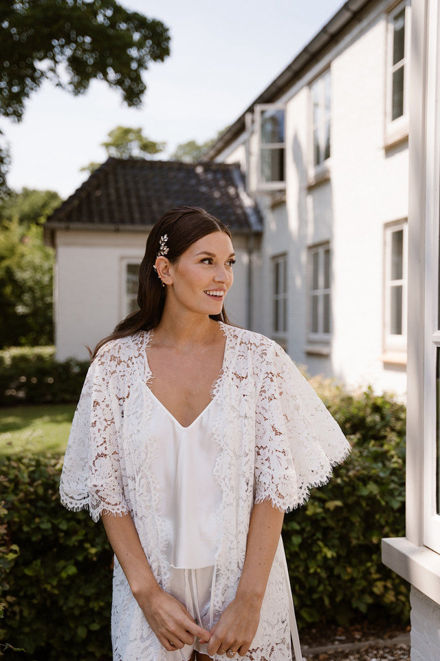 Bride in a white lace robe outside a country estate
