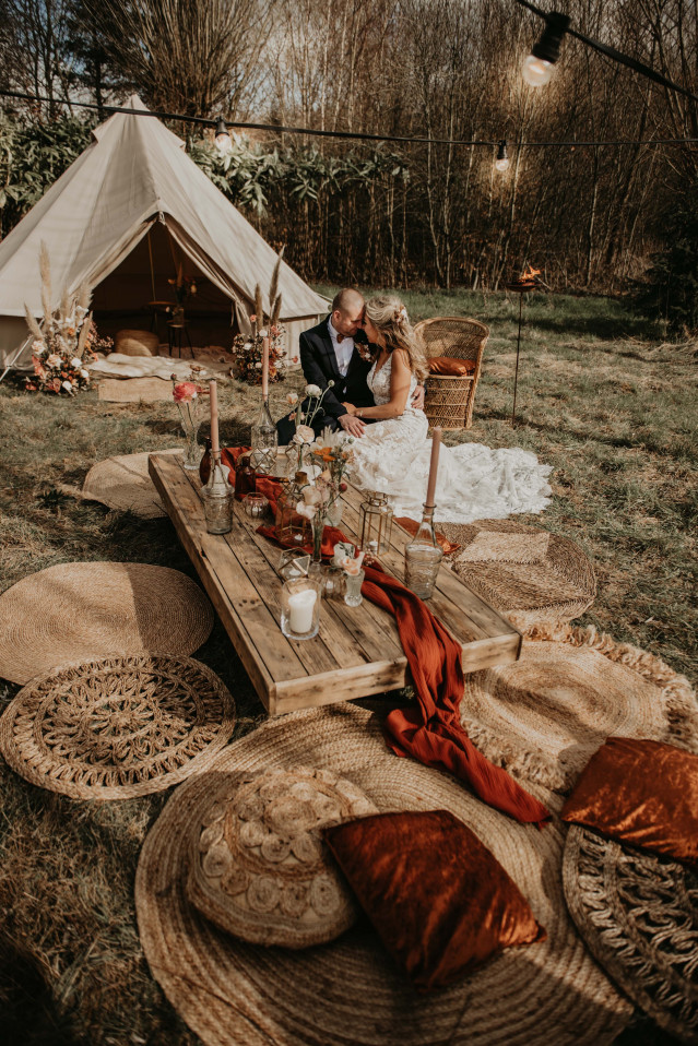 Brautpaar sitzend auf Boho Style Kissen bei einer Hochzeit im Freien