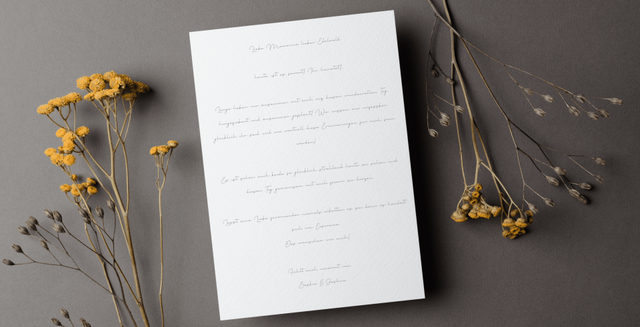 Hochzeitskarte beschrieben mit eleganter Schreibschrift neben Zweigen mit gelben Blumen