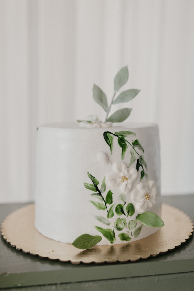 Hochzeitstorte mit Zuckerblumen und grünen Zweigen