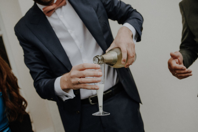 Mann schenkt Sekt aus einer Flasche in ein Sektglas