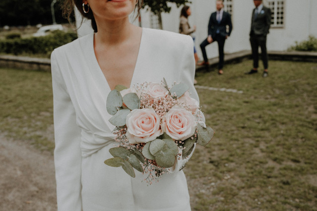 la mariée en tailleur pantalon avec le bouquet de la mariée