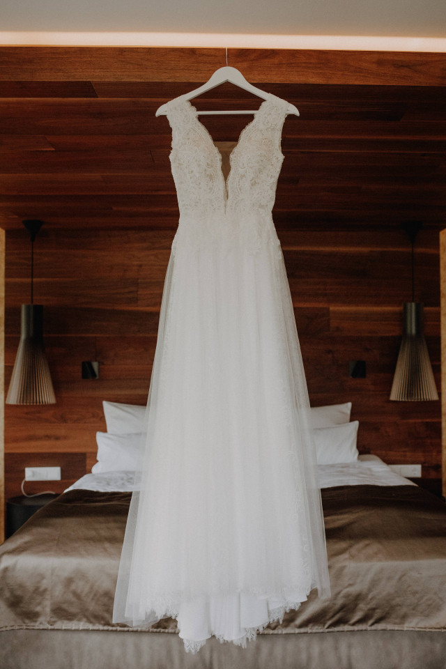 Brautkleid hängt auf Kleiderbügel vor dem Bett