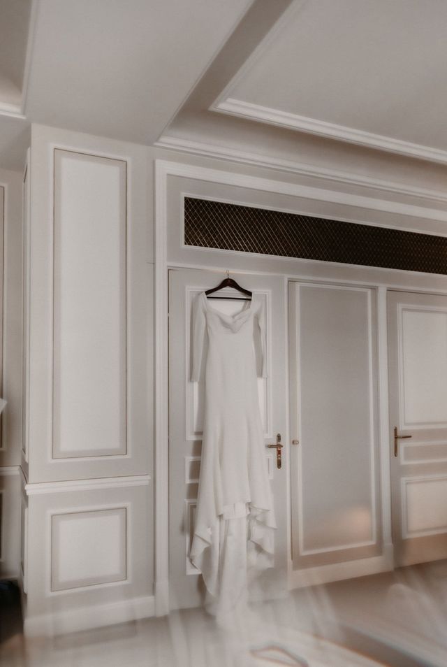 Brautkleid hängt auf einem Kleiderbügel an der Wand