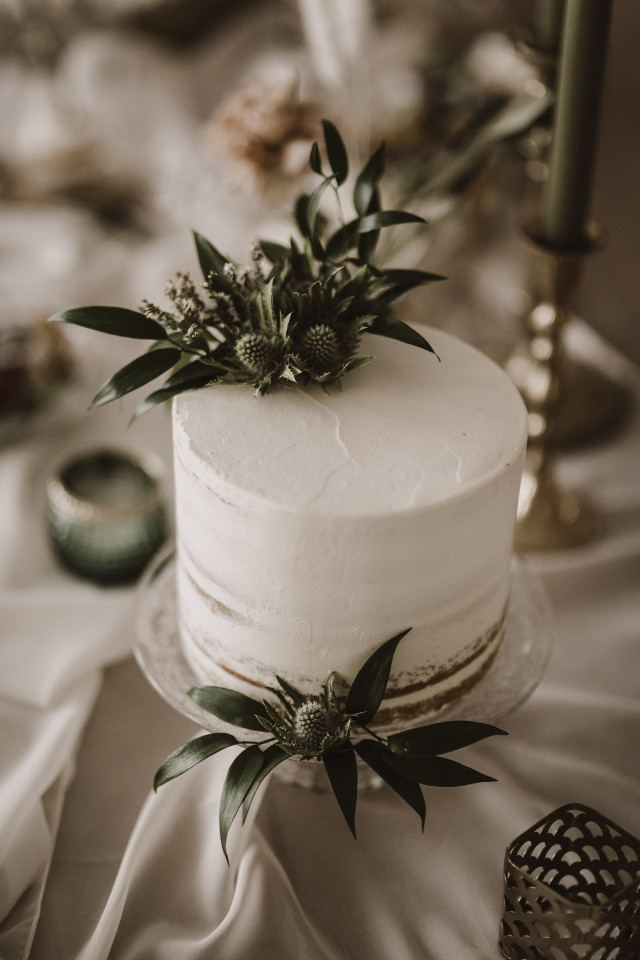 Einstöckige Hochzeitstorte mit weißer Buttercreme und grünen Blättern als Dekoration